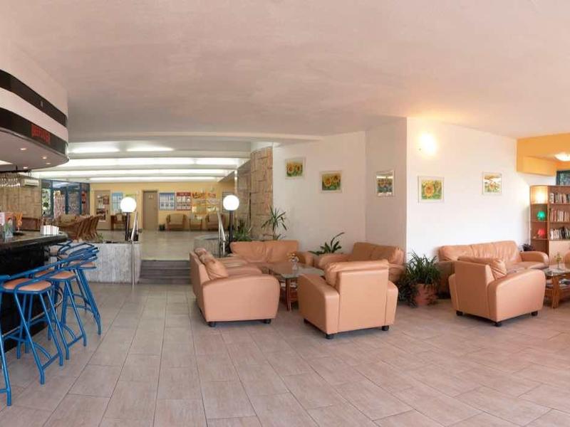 Salon d'hôtel accueillant avec tabourets de bar bleus, fauteuils confortables et grandes fenêtres.