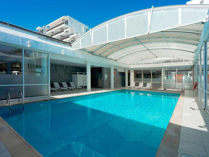 Piscine intérieure moderne avec auvent et transats dans un hôtel.