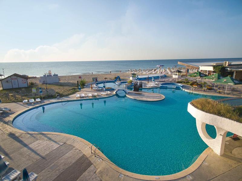 Grande piscine extérieure avec terrasse ensoleillée et vue sur la mer par une journée ensoleillée