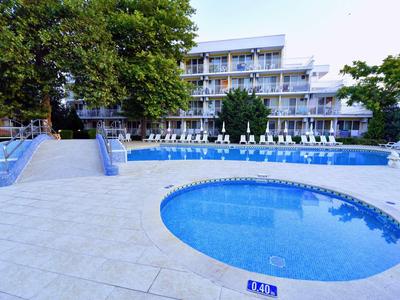 Moderner Hotelkomplex mit Schwimmbad, Whirlpool und Sonnenterrasse unter Blauem Himmel.