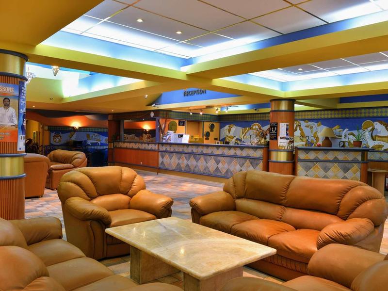 Accogliente lounge dell'hotel con divani in pelle beige e tavolo quadrato in marmo.