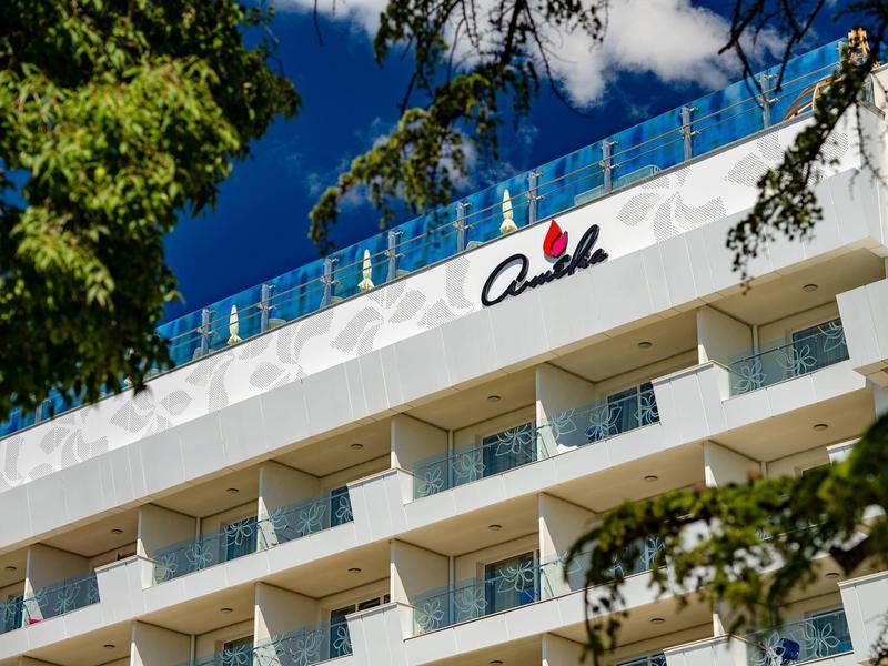 Pohled na bílou fasádu hotelu s balkony a nápisem na střeše.