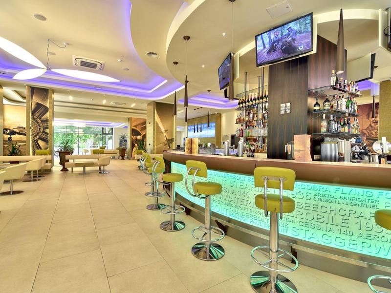 Moderní hotelový bar s osvětleným pultem a sezením v světlém prostředí.