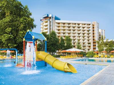 Hotel s velkým bazénem a vodním hřištěm s skluzavkou pod modrou oblohou