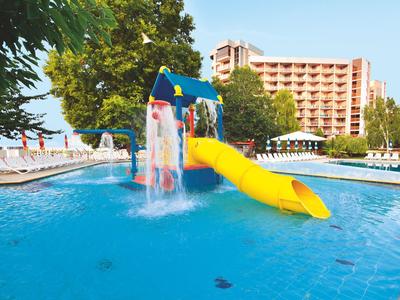 Widok przez drzwi na jasny pokój hotelowy z widokiem na morze i łazienkę z wanną.