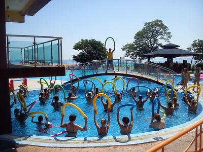 Ludzie ćwiczą aqua aerobik w odkrytym basenie hotelowym z widokiem na morze