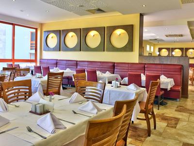 Nowoczesna restauracja z nakrytymi stołami i drewnianymi krzesłami w jasnych kolorach.