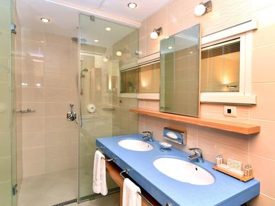 Moderní koupelna s modrým dvojumyvadlem a skleněným sprchovým koutem.