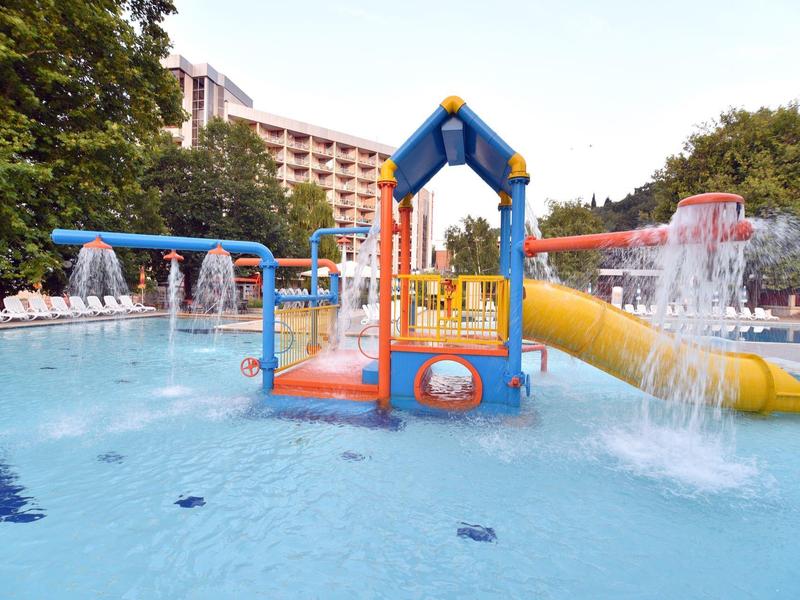 Barevné vodní hřiště s tobogány a vodními prvky v hotelovém venkovním bazénu.