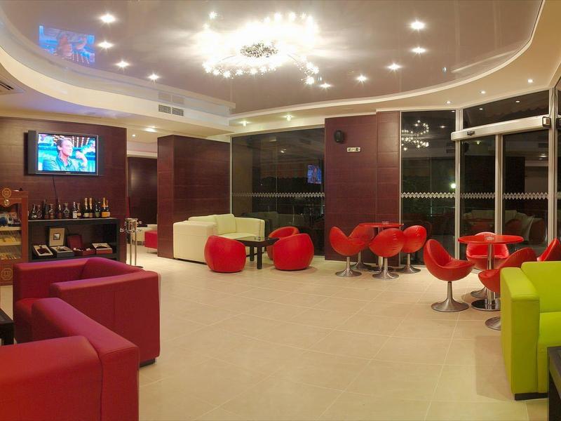 Moderní hotelová lobby s barevnými křesly a odpočinkovými zónami pod jasným stropním osvětlením.