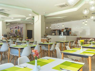 Moderner Speiseraum mit weißen Wänden, Holzstühlen und grünem Tafeldekor.