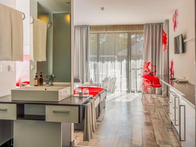 Modern eingerichtetes Hotelzimmer mit Schreibtisch, Stühlen und Bodenbelag aus Holz.