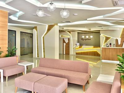 Heller Lounge-Bereich mit rosa Sitzmöbeln, Pflanzen und modernem Deckenlichtdesign.