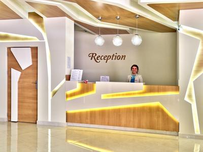 Moderní hotelová recepce s osvětlenou přepážkou a přátelským personálem.