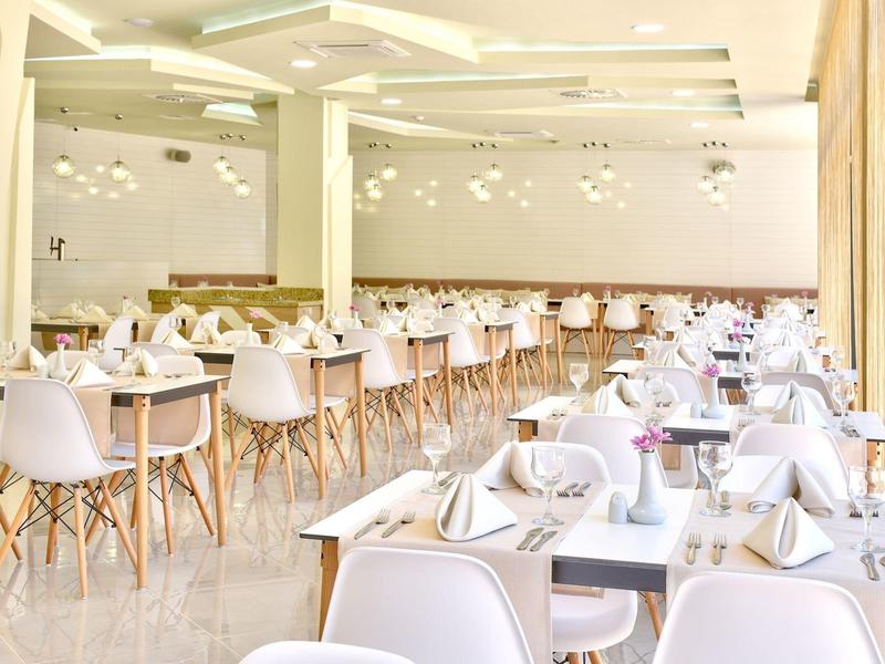 Helles, modernes Restaurant mit weißen Tischen, Stühlen und großen Spiegeln an den Wänden.