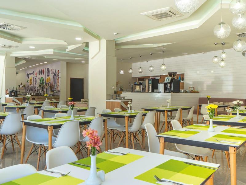 Moderner Speiseraum mit weißen Wänden, Holzstühlen und grünem Tafeldekor.