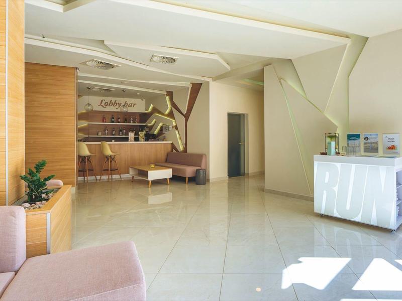 Heller und moderner Hotel-Empfangsbereich mit Rezeption, Sitzgelegenheiten und stilvoller Dekoration.