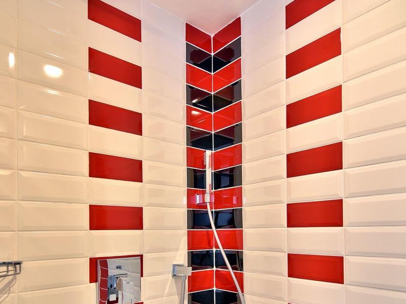 Dusche mit weißen Fliesen und roten Streifen, moderne Regendusche in der Raumecke installiert.