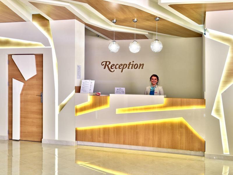 Moderne Empfangstheke mit Holz, weißem Design, LED-Beleuchtung und freundlicher Empfangsdame.