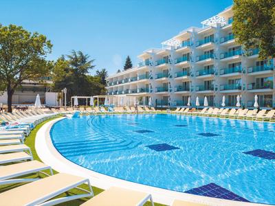 Modern hotelzwembad met ligstoelen en balkons op een zonnige dag