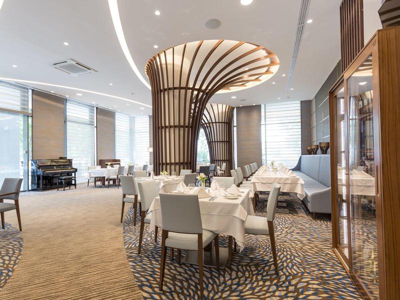 Moderní hotelová restaurace s elegantním krbem a stylově prostřenými stolky.