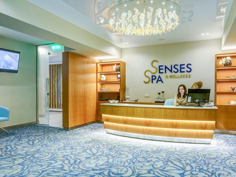 Moderní spa recepce s pultem a modrými sedadly.