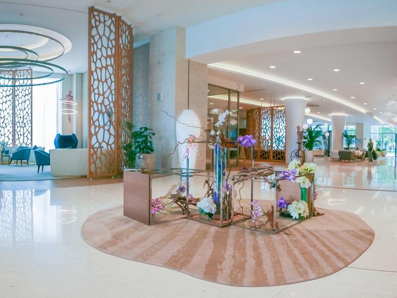 Prostorná a světlá hotelová hala s moderním zařízením a rostlinami.