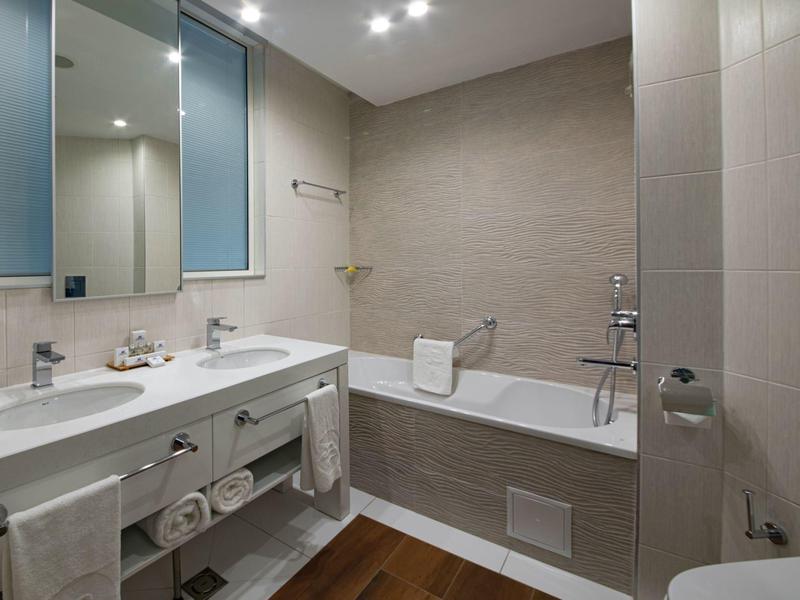 Moderní koupelna s vanou, dvojitým umyvadlem a velkými zrcadly.