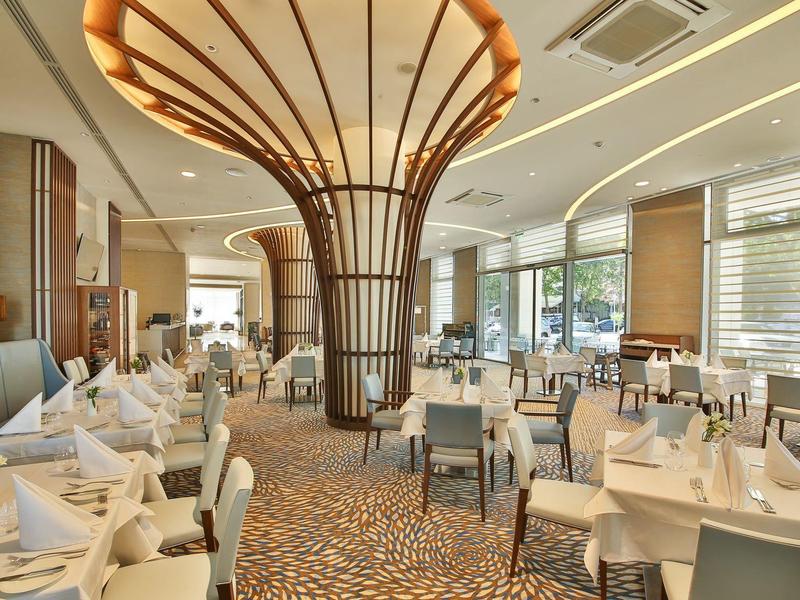 Elegantní hotelová restaurace s stylovými stoly a moderním osvětlením.