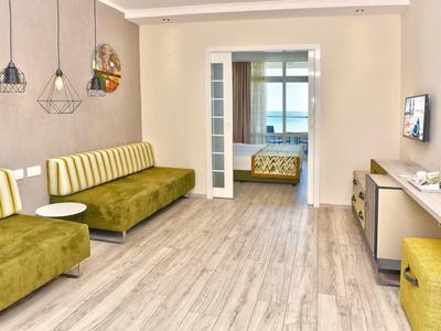 Una habitación de hotel moderna con sofás verde amarillentos y suelo de madera clara.