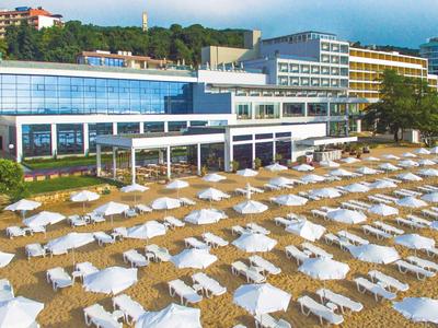 Playa con muchas sombrillas blancas frente a un gran hotel junto al mar.