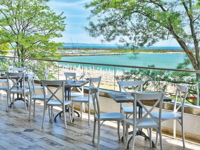 Terraza con mesas y sillas con vista a la playa y el mar en un día soleado.