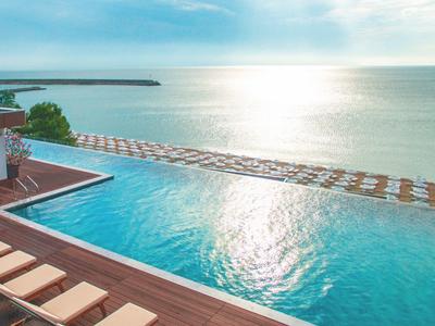 Piscina infinita con vista al mar y reflejo de luz solar en la costa.