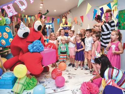 Niños en fiesta de cumpleaños con disfraz de cangrejo rojo y decoración colorida.
