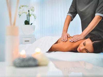 Mujer recibe masaje relajante de espalda en ambiente de spa luminoso y tranquilo.