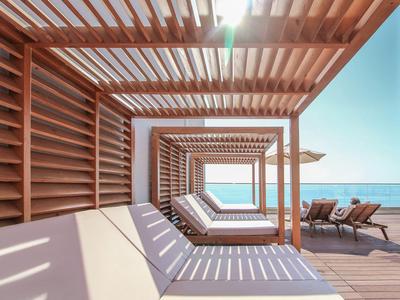 Moderne strandpaviljoen met houten latten en ligstoelen met uitzicht op zee.