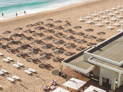 Leeg strand met gerangschikte ligbedden en parasols naast een gebouw aan zee.