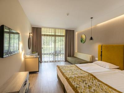 Modernes Hotelzimmer mit zwei Betten, gelbem Kopfteil und großem Fenster mit Blick auf Balkon.