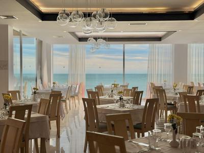 Helles Restaurant mit Holzstühlen und großen Fenstern mit Meerblick.