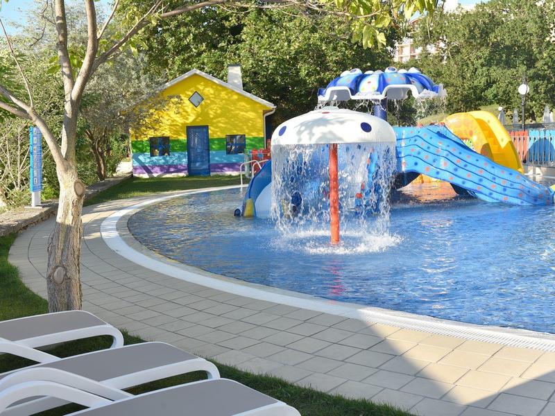 Parque acuático colorido para niños con toboganes en área exterior soleada.