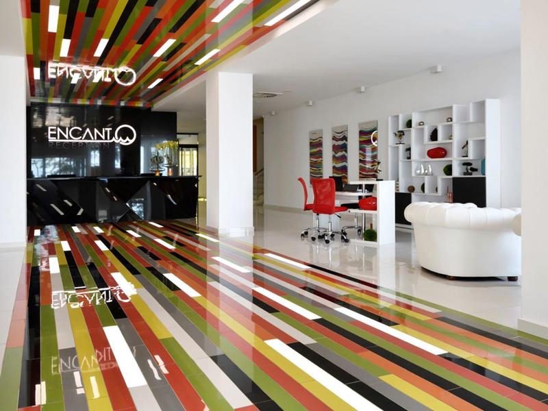 Área de recepción moderna con patrón de rayas coloridas en el suelo y el techo de un hotel.