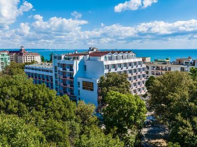 Vista de un hotel costero con vista al mar, rodeado de árboles verdes.