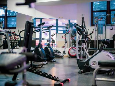 Moderne Fitnessgeräte in einem hellen, gut ausgestatteten Fitnessraum mit großen Fenstern.