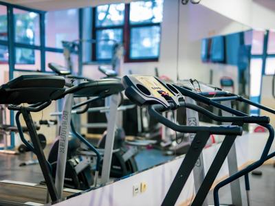 Moderne Trainingsgeräte in einem hellen Fitnessstudio mit großen Fenstern.