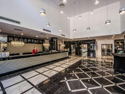 Amplia recepción de hotel con diseño moderno y suelo de mármol blanco y negro.