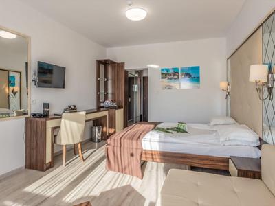 Habitación de hotel luminosa con cama doble, escritorio y mobiliario moderno.