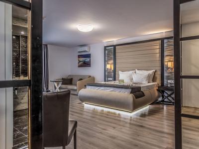 Habitación de hotel moderna con cama grande, sofá y suelo de madera.