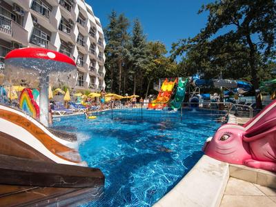 Blick auf einen Hotelpool mit Wasserrutschen und bunten Wasserfontänen an einem sonnigen Tag.