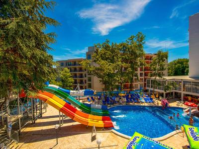 Hotelpool mit buntem Wasserrutschen und Liegestühlen unter blauem Himmel.