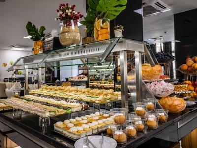 Buffet con variedad de pasteles, pan y magdalenas en un restaurante de hotel moderno.